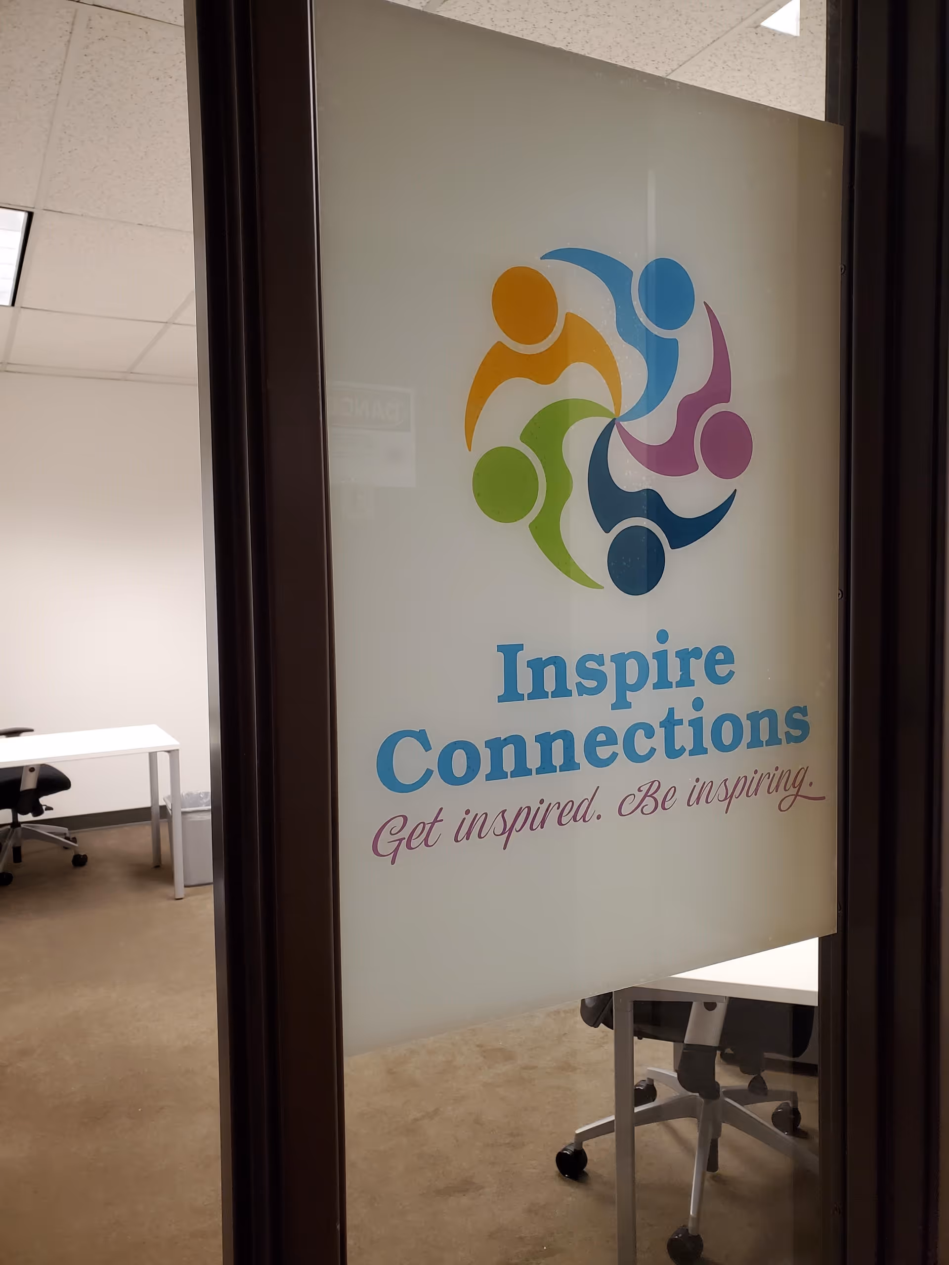 Frosted glass door shows Inspire Connections logo with office desk and chair behind.