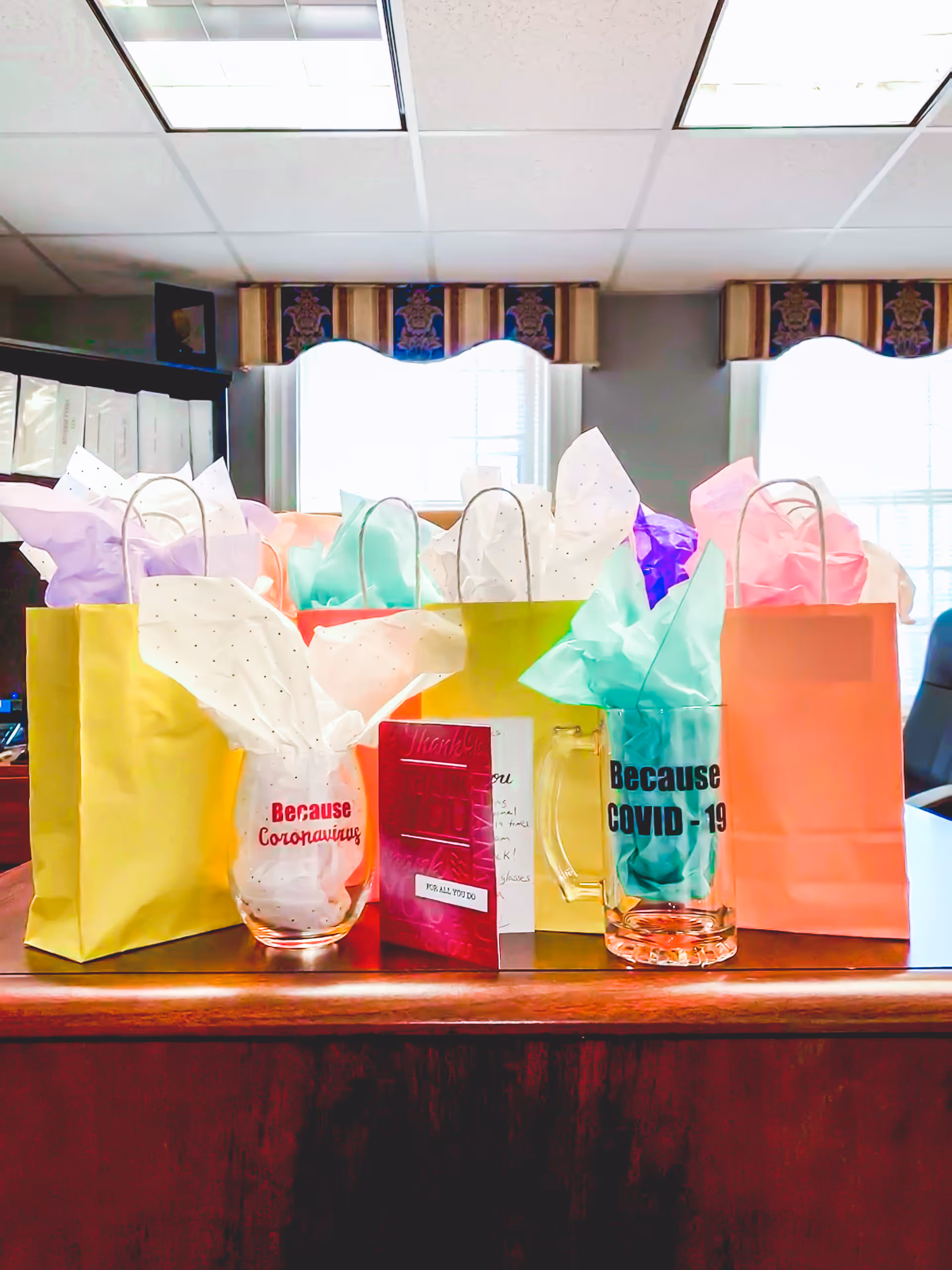 Colorful gift bags with tissue paper on a wooden table in a bright room.