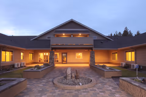 Exterior view of The Lodge at Fairway Forest with a lit entry and courtyard planters.