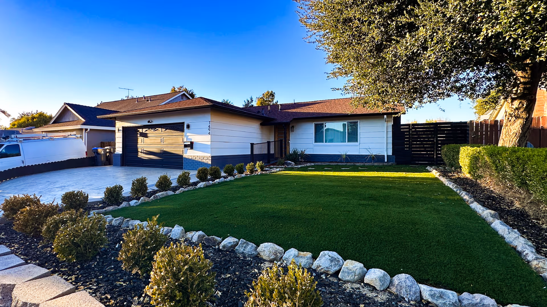 A single-story home with a manicured lawn, rock borders, and a driveway.