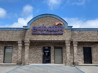 Brick hospice building with arched purple Enhabit sign and front entrance.
