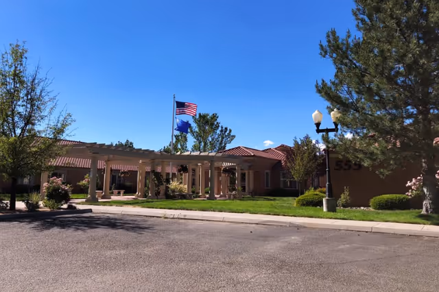 Exterior view of Alta Skilled Nursing and Rehabilitation Center with a columned entrance and flags.