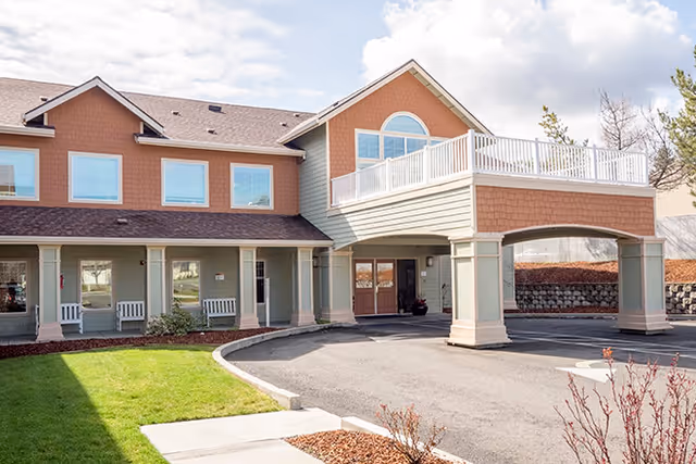 Exterior view of Siskiyou Springs Assisted Living Community entrance with curved driveway and balcony.