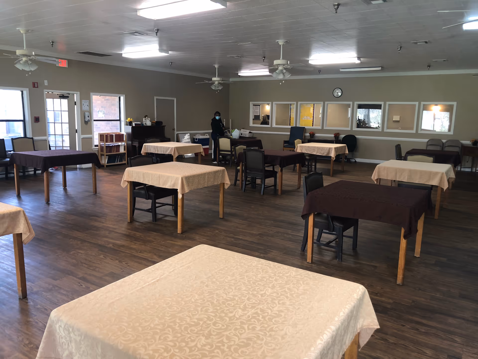Spacious indoor dining room with multiple tables covered in beige and brown cloths.