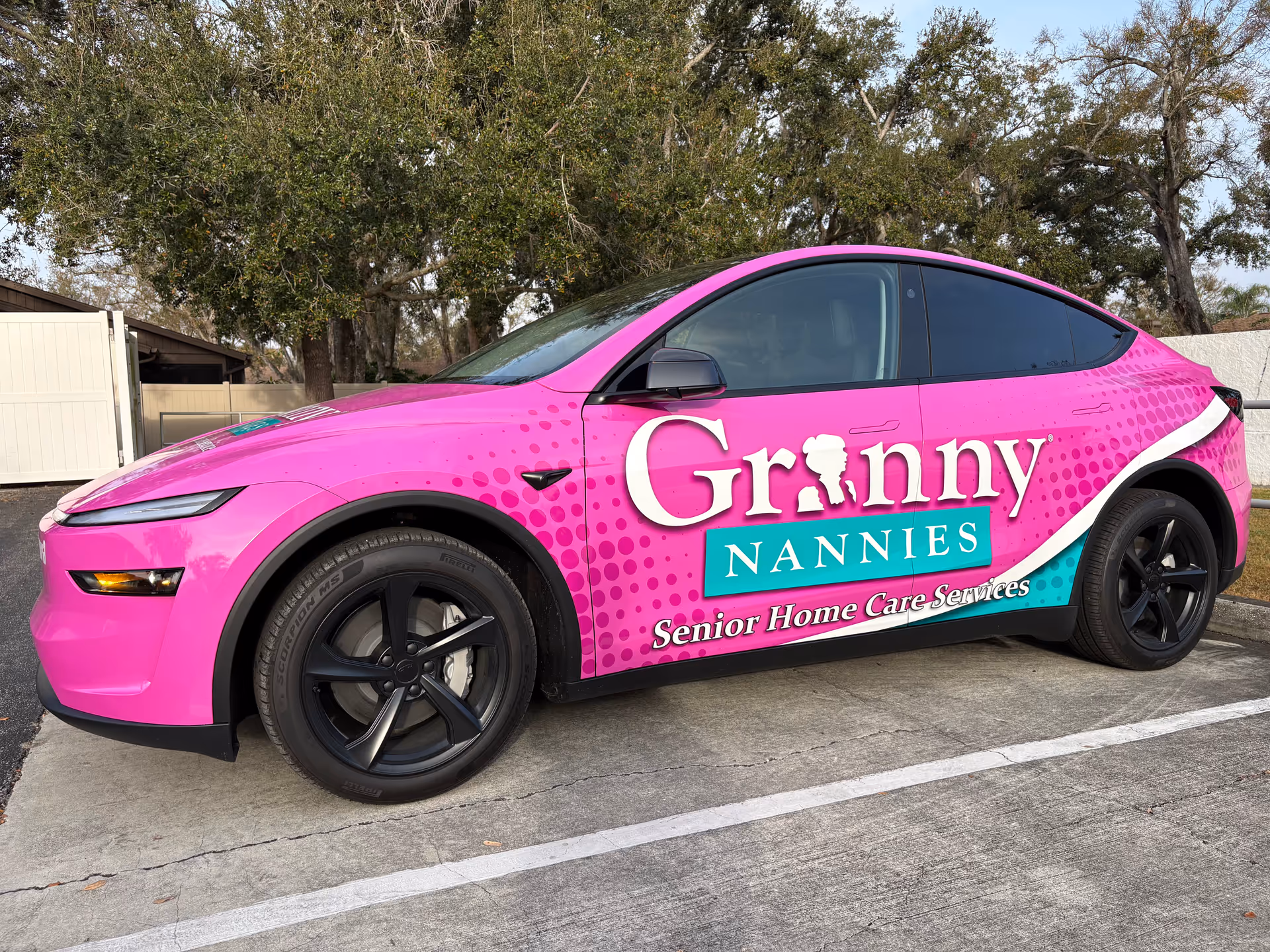 Bright pink Granny Nannies car with Senior Home Care branding parked in a lot.