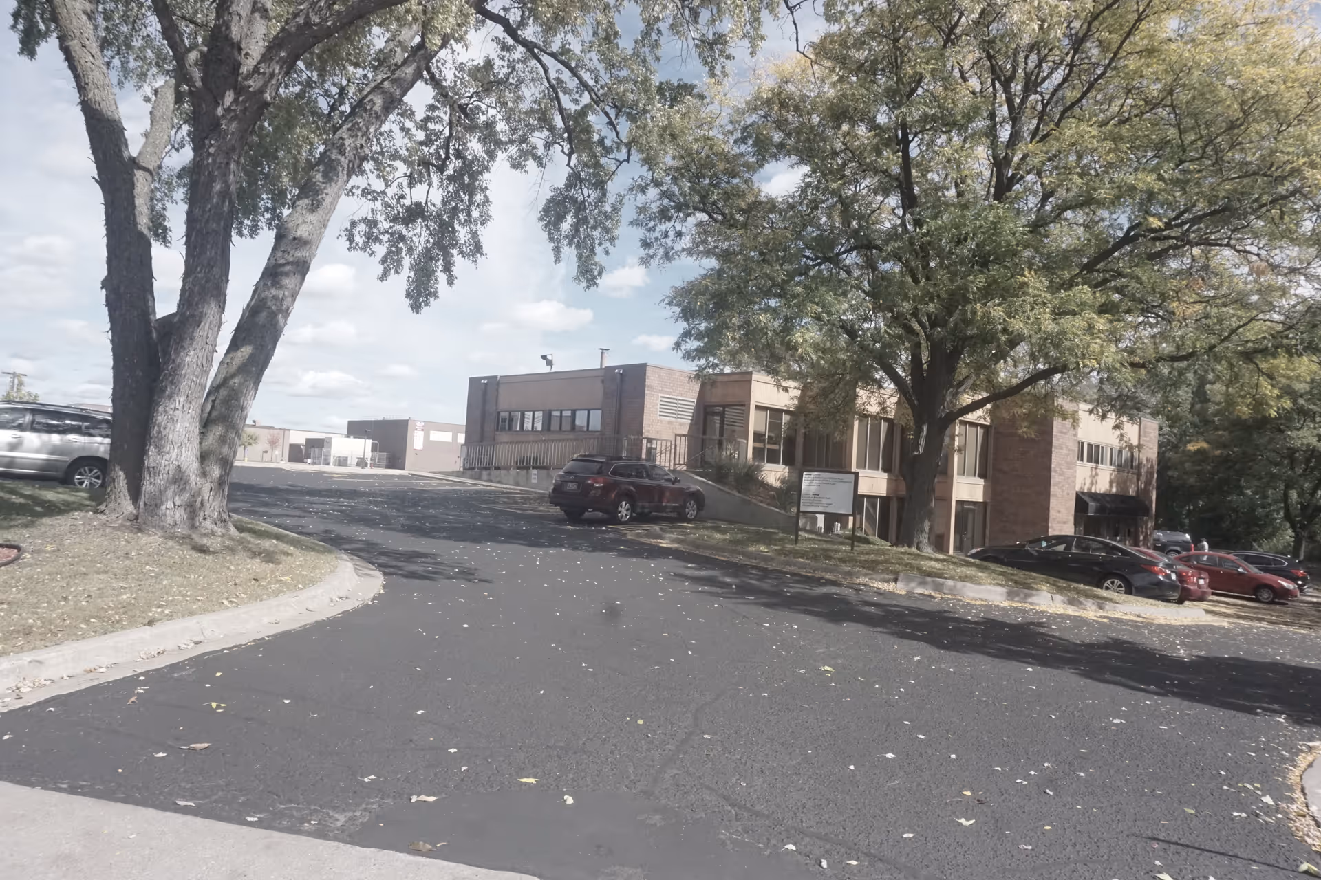 Exterior view of a brick senior living facility with parking and trees.