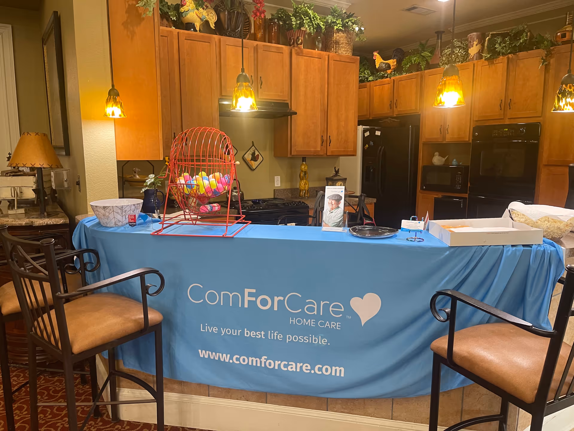 Blue ComForCare banner on a table in a warm kitchen with wooden cabinets