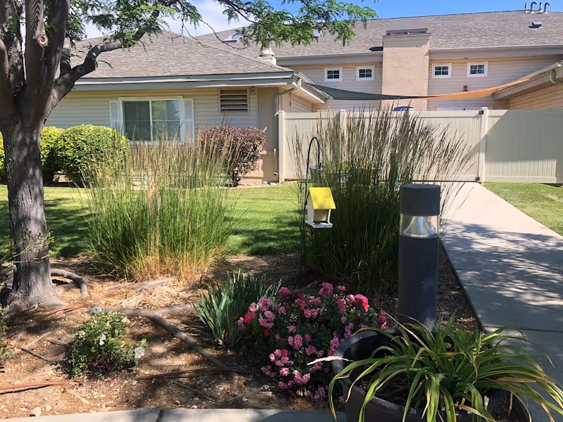 Exterior of a senior living facility with garden and walkway.