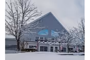 Snow-covered exterior of The Golden Crest facility with an arched window and entrance.