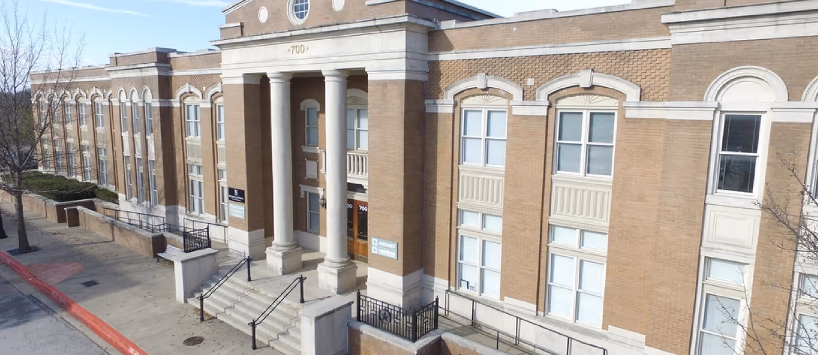 Exterior view of a brick building with tall columns and a grand entrance stairway.