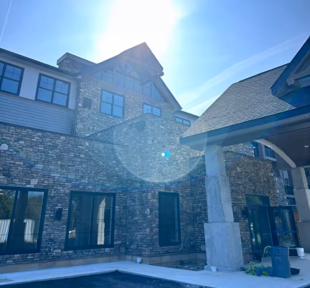 Stone-clad senior living facility front with large windows and sunlit entrance.
