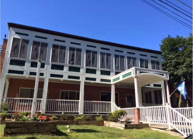 Front view of Waban Health Center, a brick building with a covered entrance and white trim.