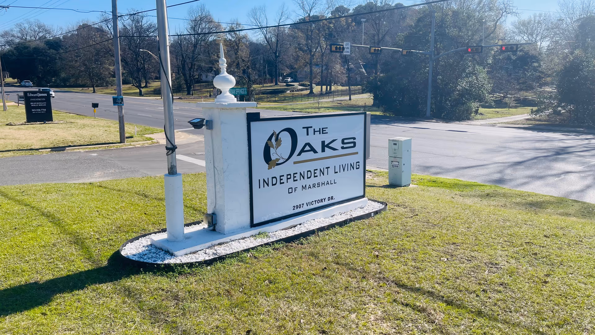 Outdoor roadside sign for The Oaks Independent Living of Marshall, near traffic signals.
