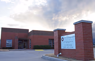 Brick building front with sign and drive-up entrance under cloudy sky.
