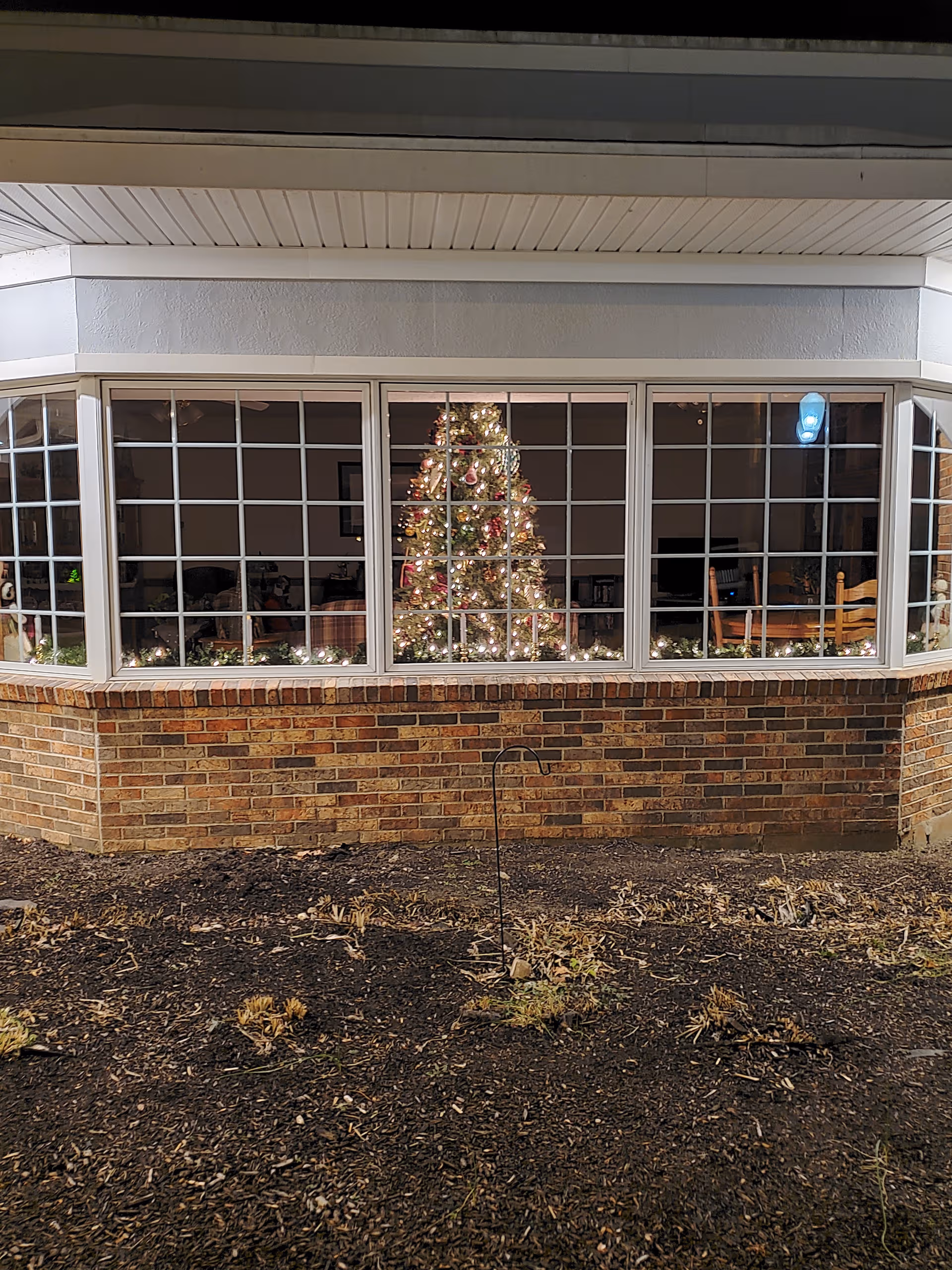 Brick exterior with wide windows showing a decorated Christmas tree inside.