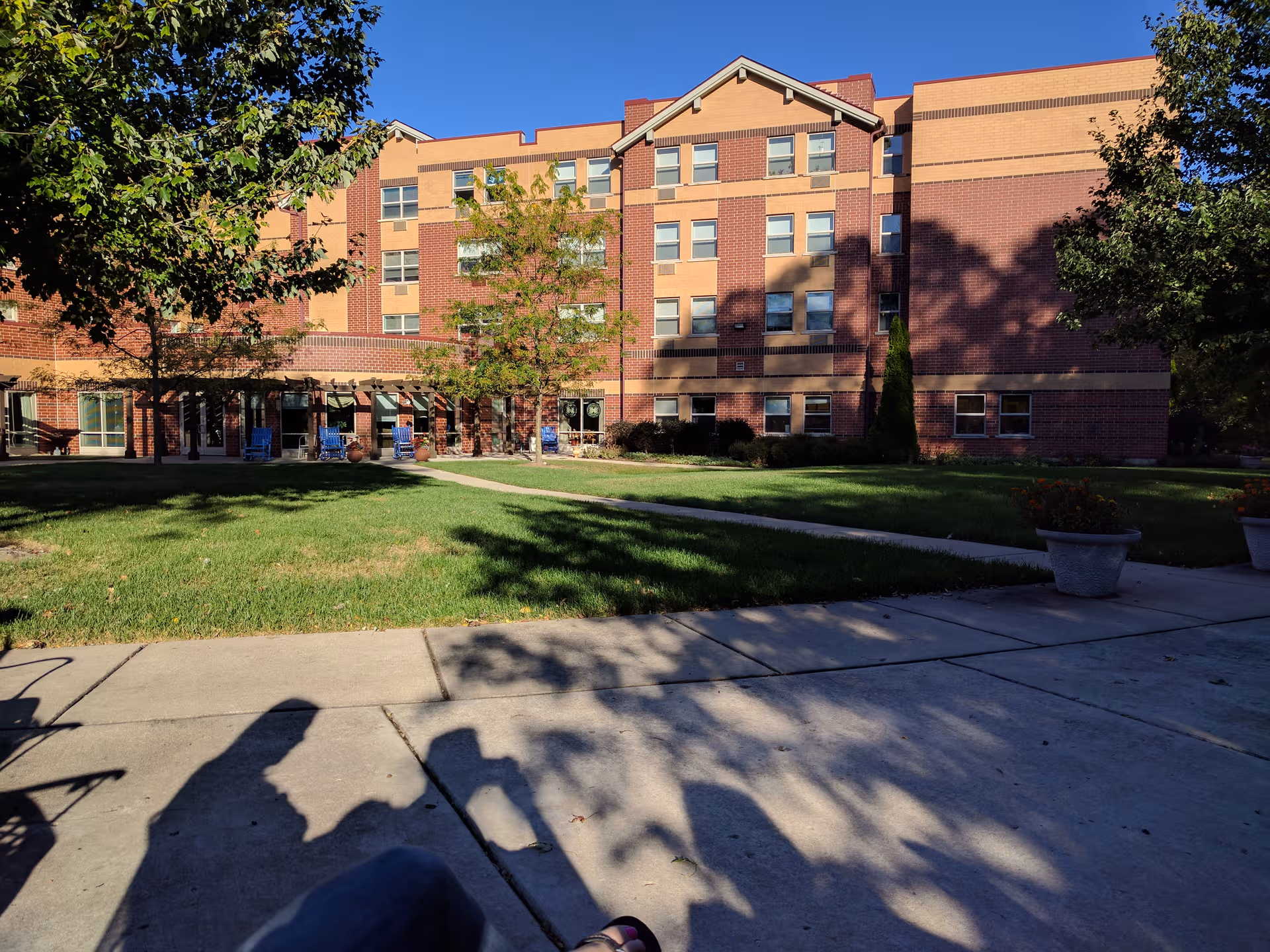Exterior view of Barton Senior Residences-Zion with brick building, lawn, trees, and walkway.