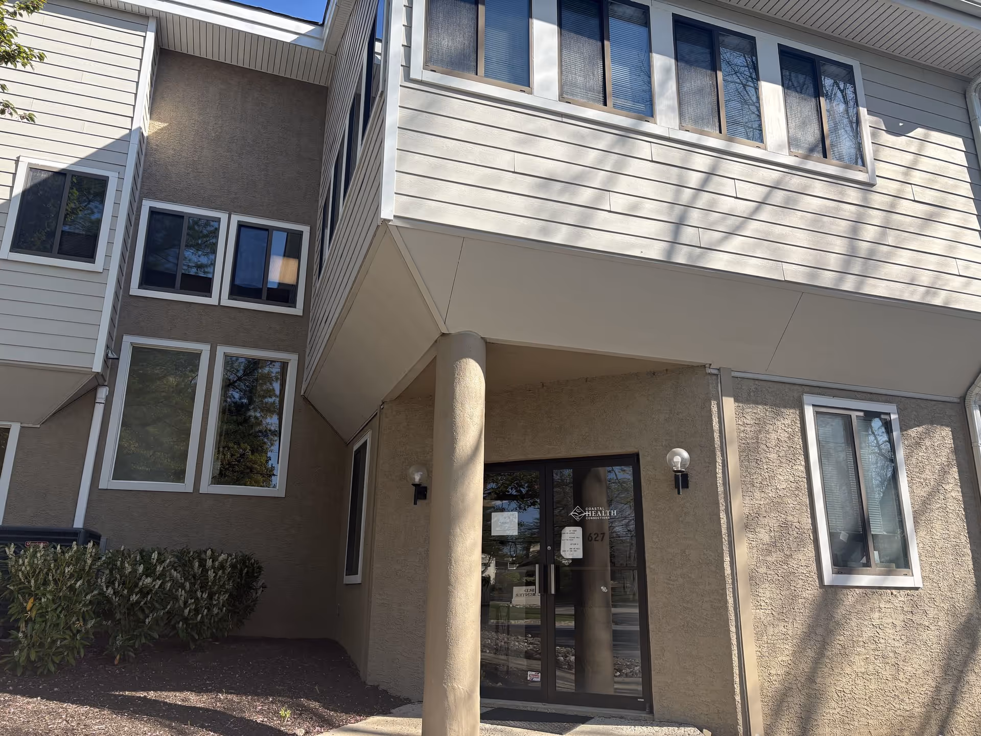 Exterior view of Coastal Health Connections entrance with glass doors, windows, and a rounded column.