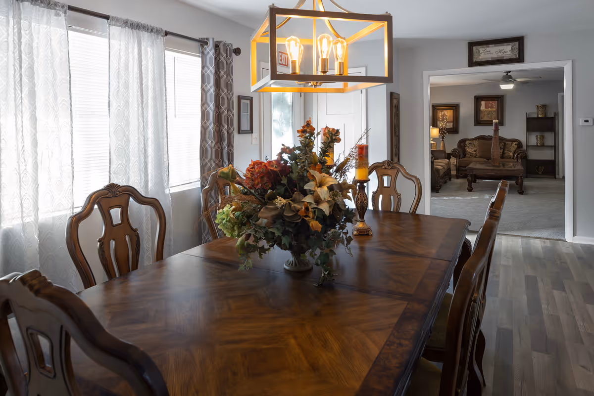 A large wooden dining table with a floral centerpiece in a bright dining room.