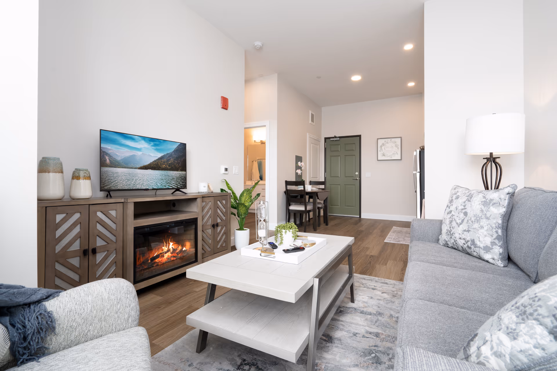 Open living room with gray sofa, coffee table, fireplace, and TV.