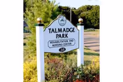 Outdoor sign for Talmadge Park Rehabilitation and Nursing Center with surrounding shrubs.