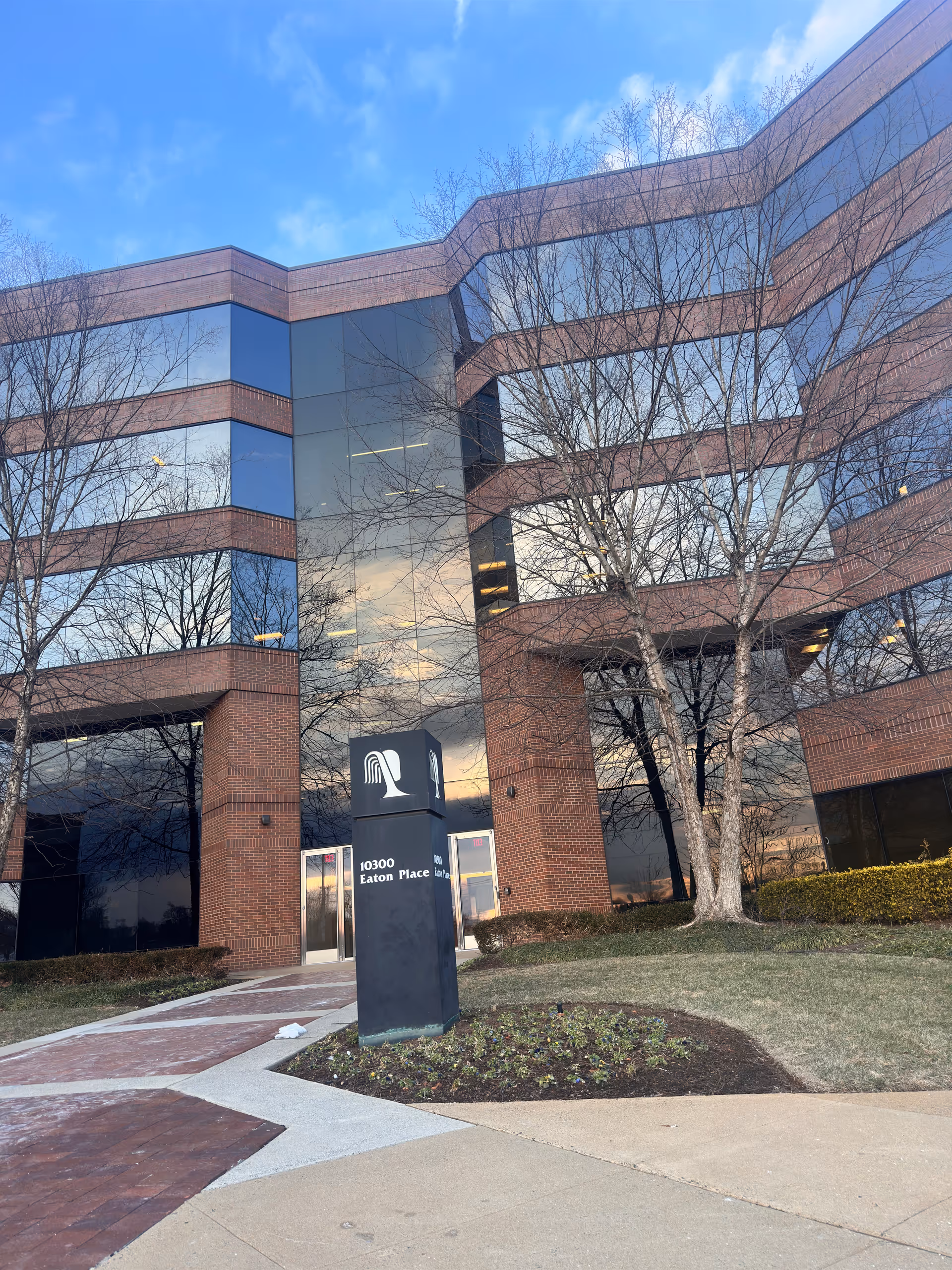 Exterior brick building with glass windows and a tall entrance sign.