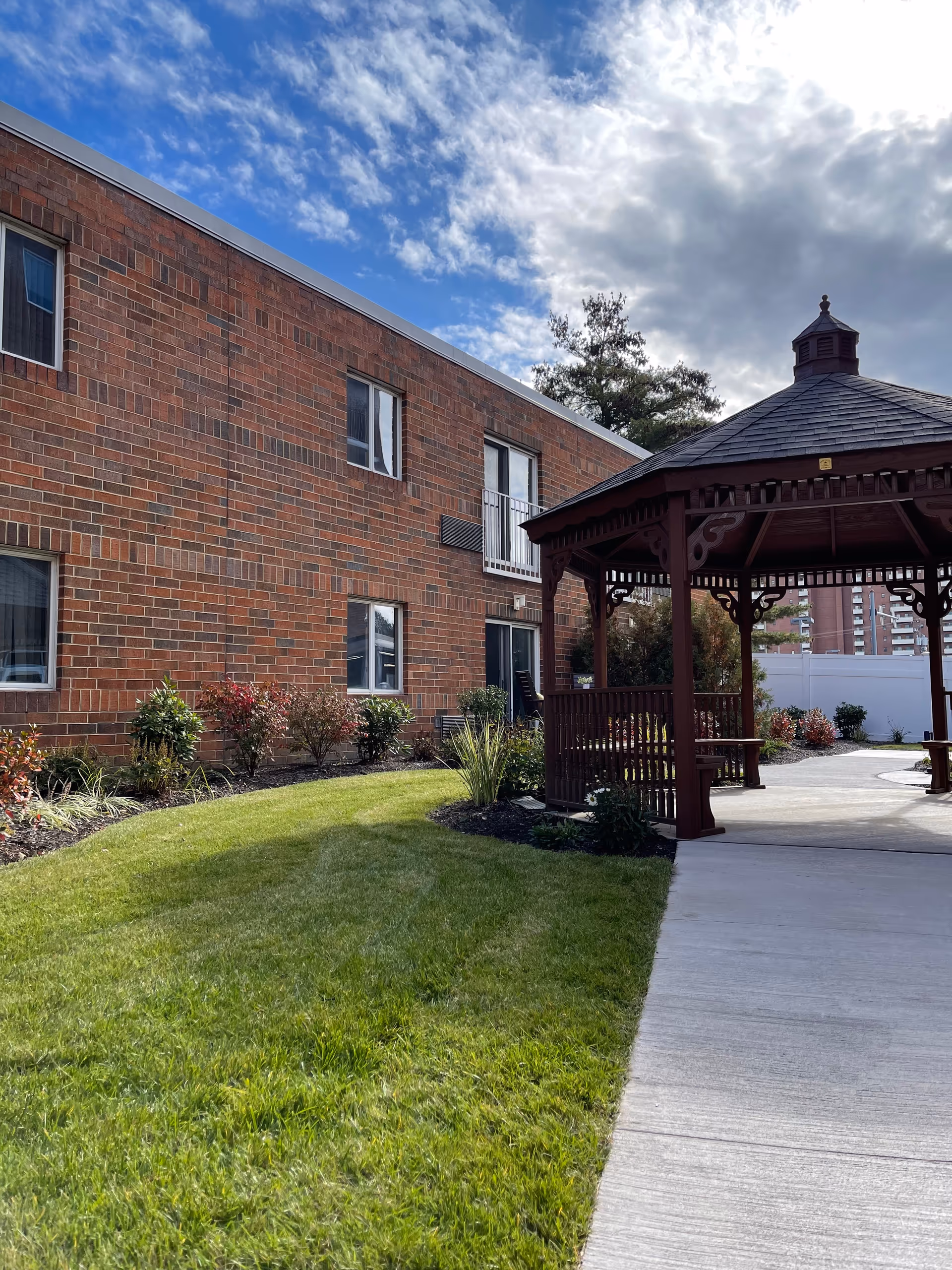Brick senior living facility with a wooden gazebo in a landscaped courtyard