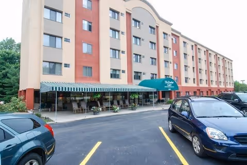 Exterior view of a multi-story senior living facility named The Parker at Rocky River Village with a covered entrance, several windows, and a parking lot with cars in front.