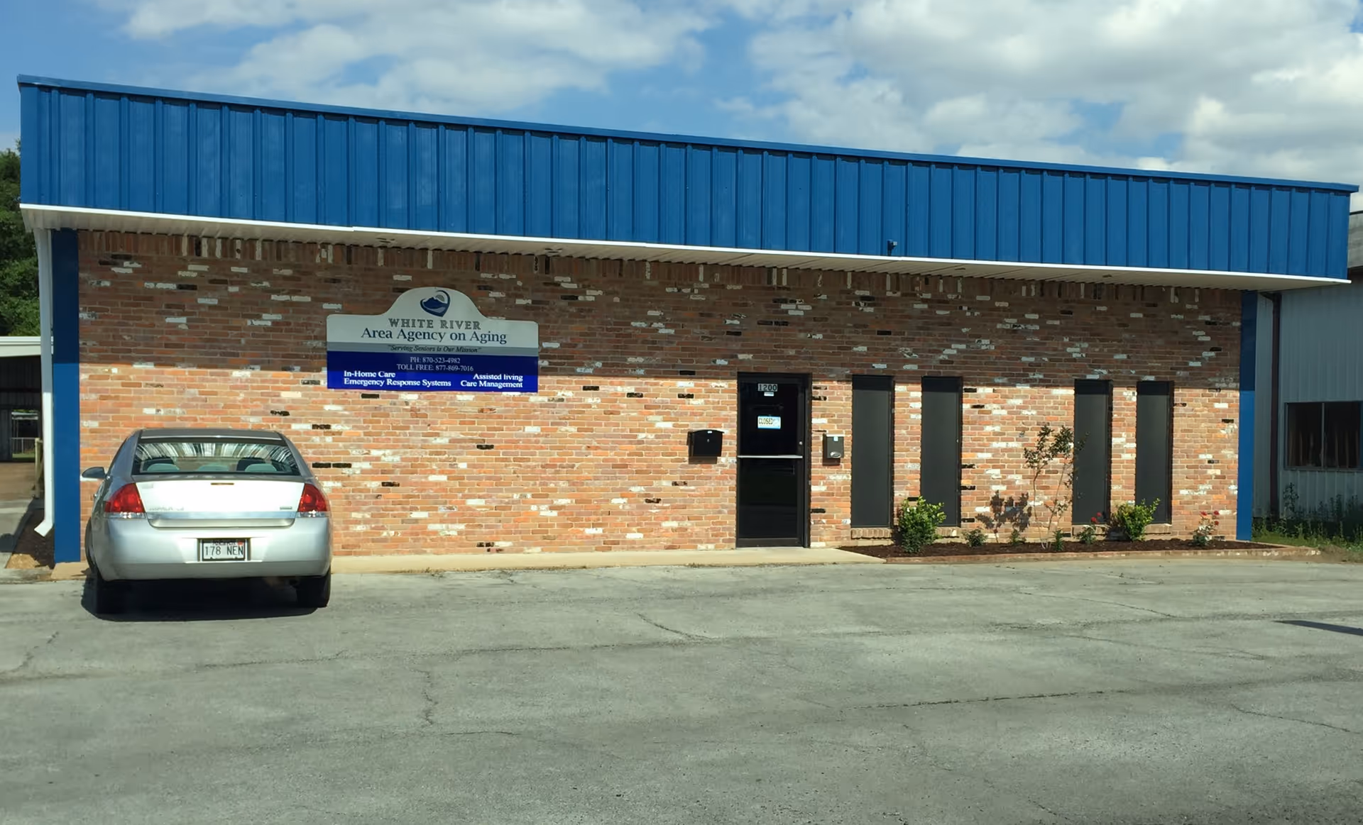 Brick building with blue roof and sign White River Area Agency on Aging; car parked outside.