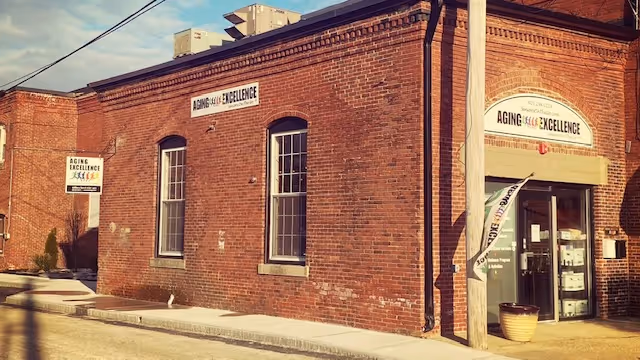 Brick Aging Excellence building exterior with sign, windows, and front doorway.