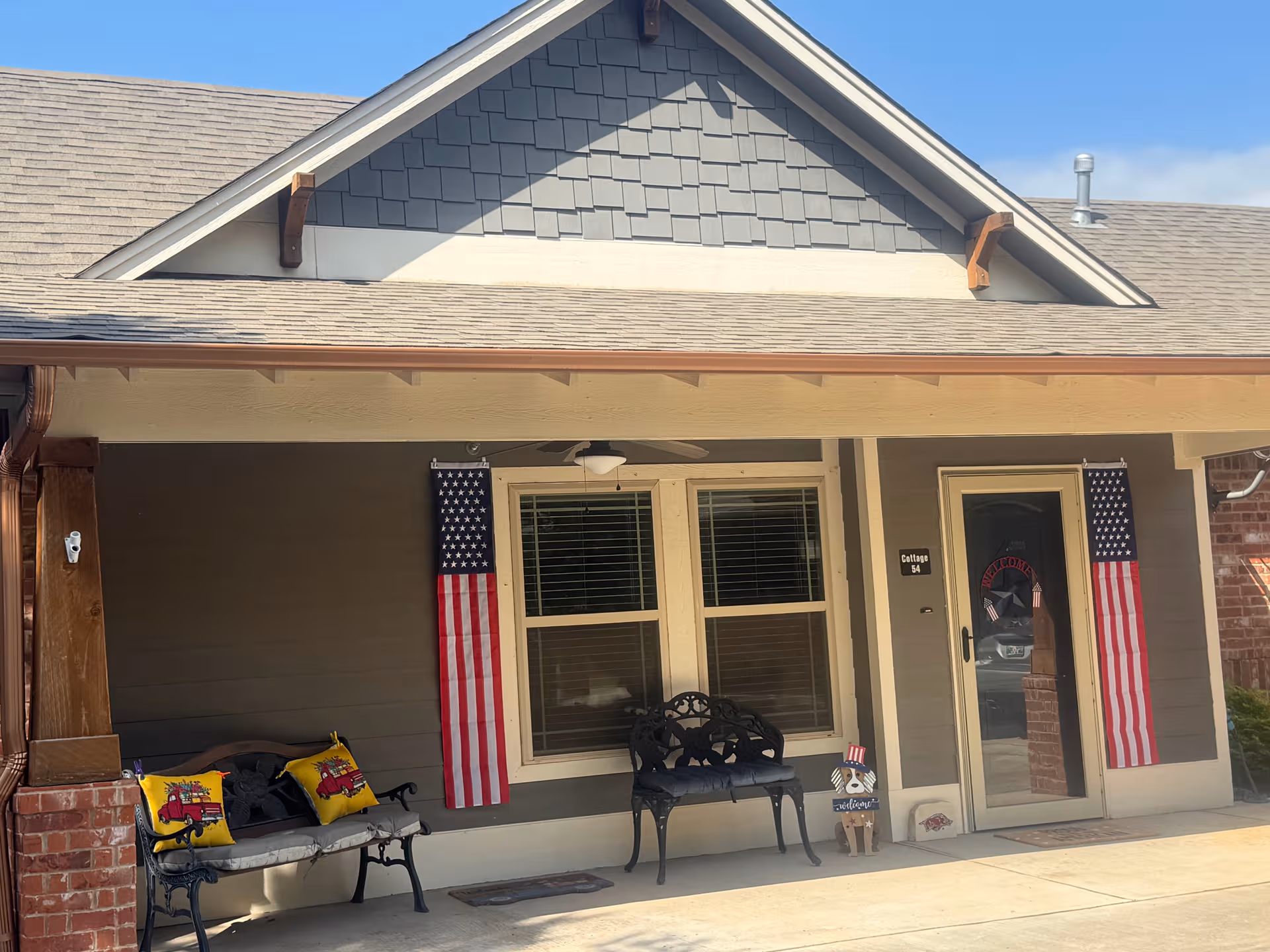 Front porch of Laurel Springs facility with two American flags, benches, and door.