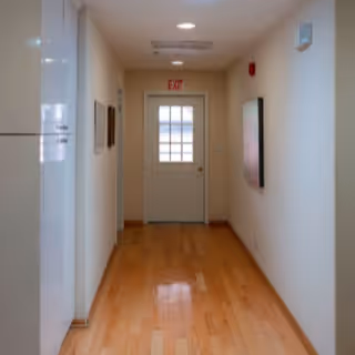 Clean, well-lit hallway with wooden floors leading to a door labeled EXIT.