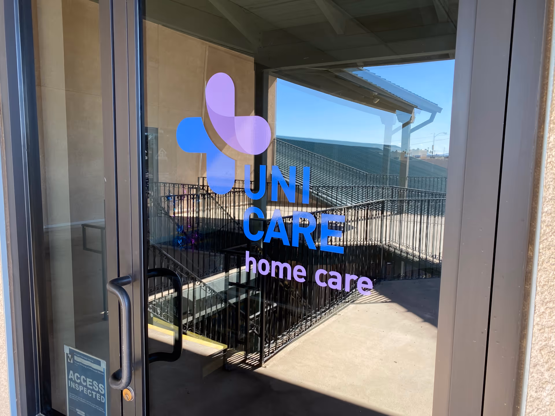 Glass door entrance with Uni Care Home Care logo and railing outside