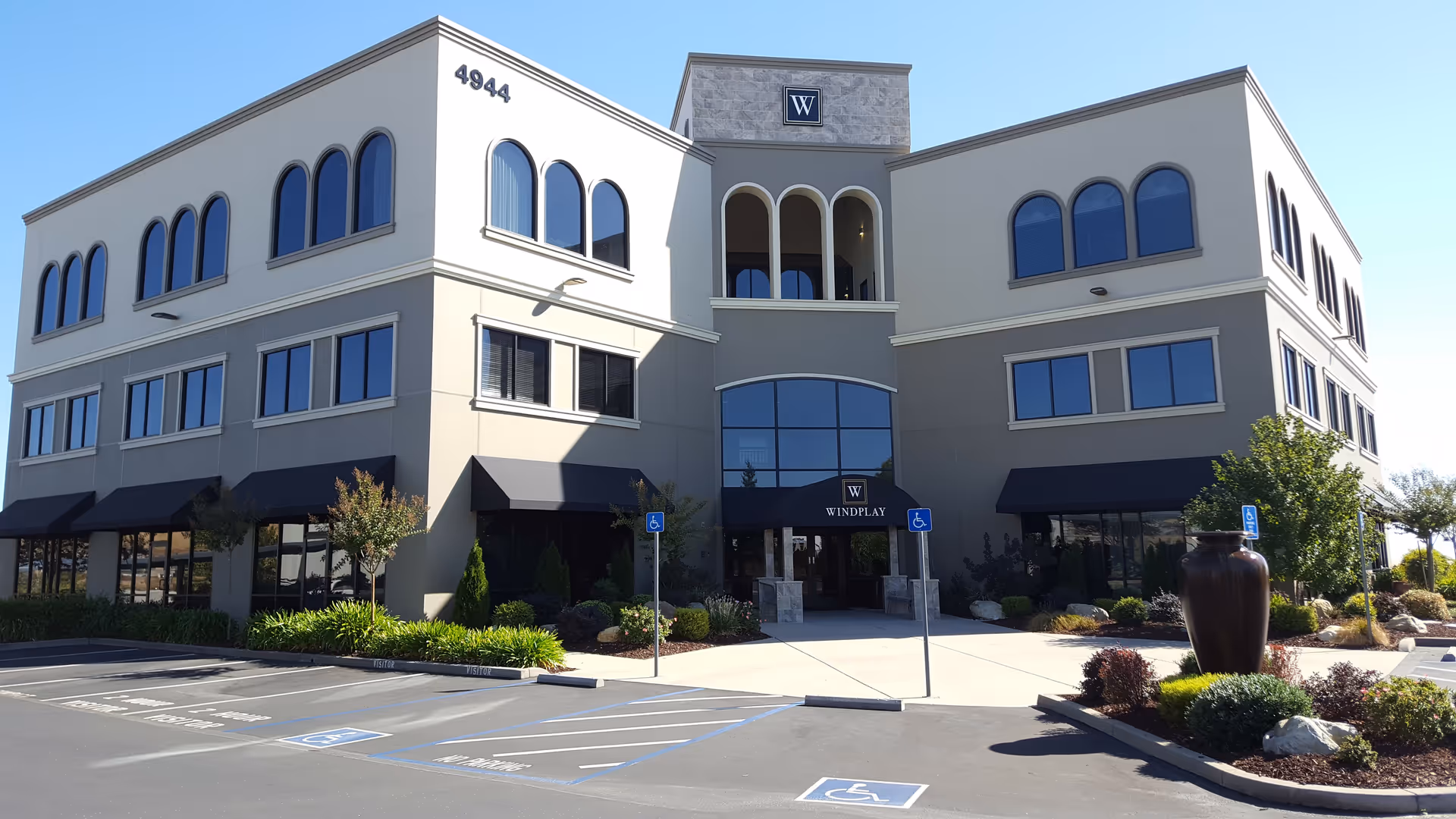 Front view of a beige multi-story building with arched windows and a glass entrance.