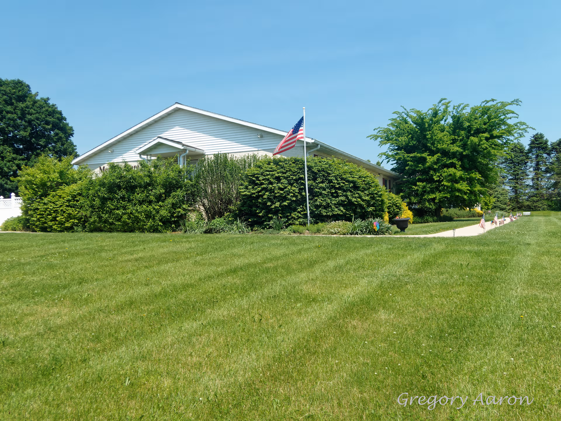Front view of a single-story facility with flag, green lawn, and shrubs.