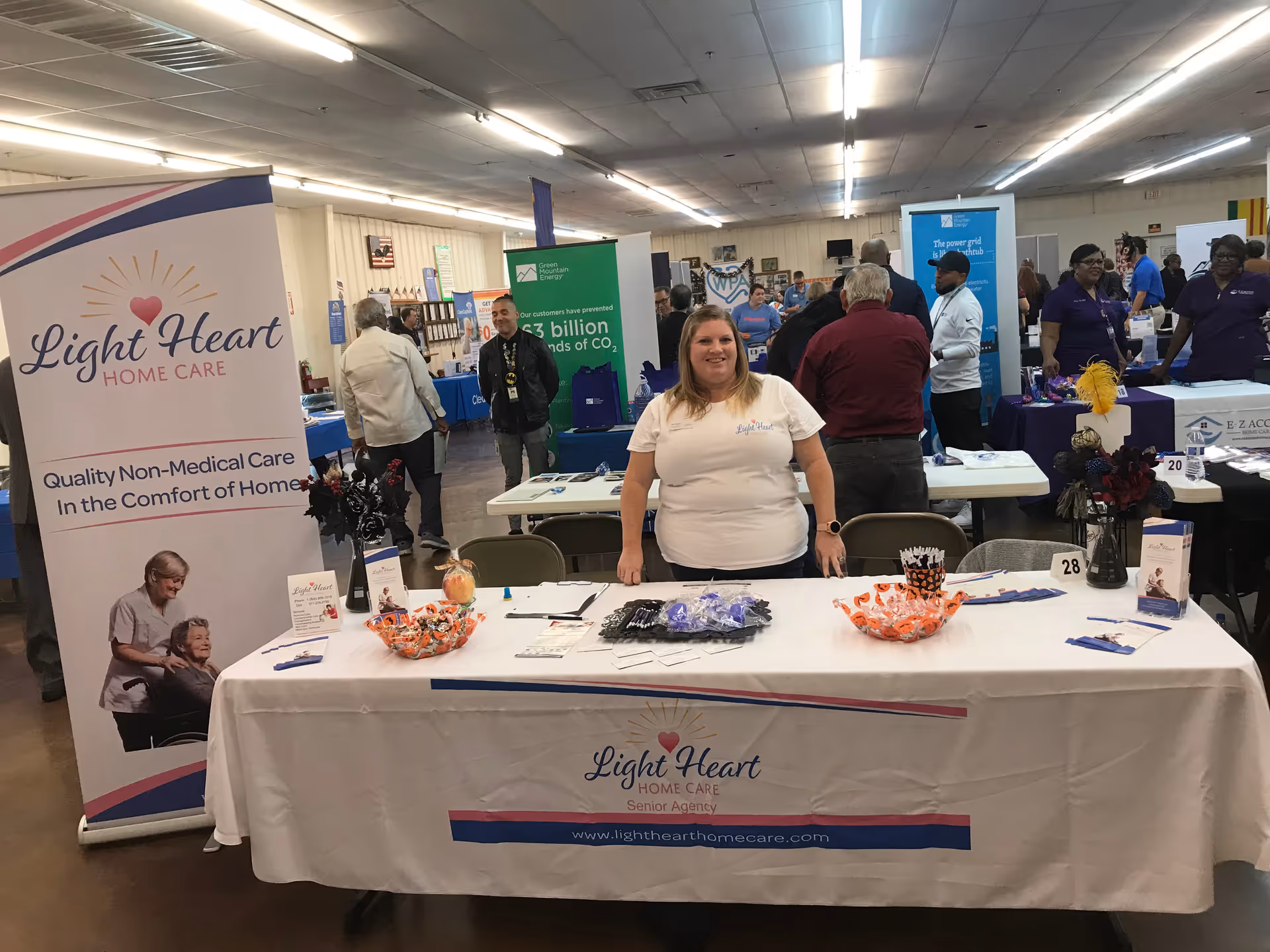 Light Heart Home Care booth at a busy expo with staff, banners, and promotional materials.