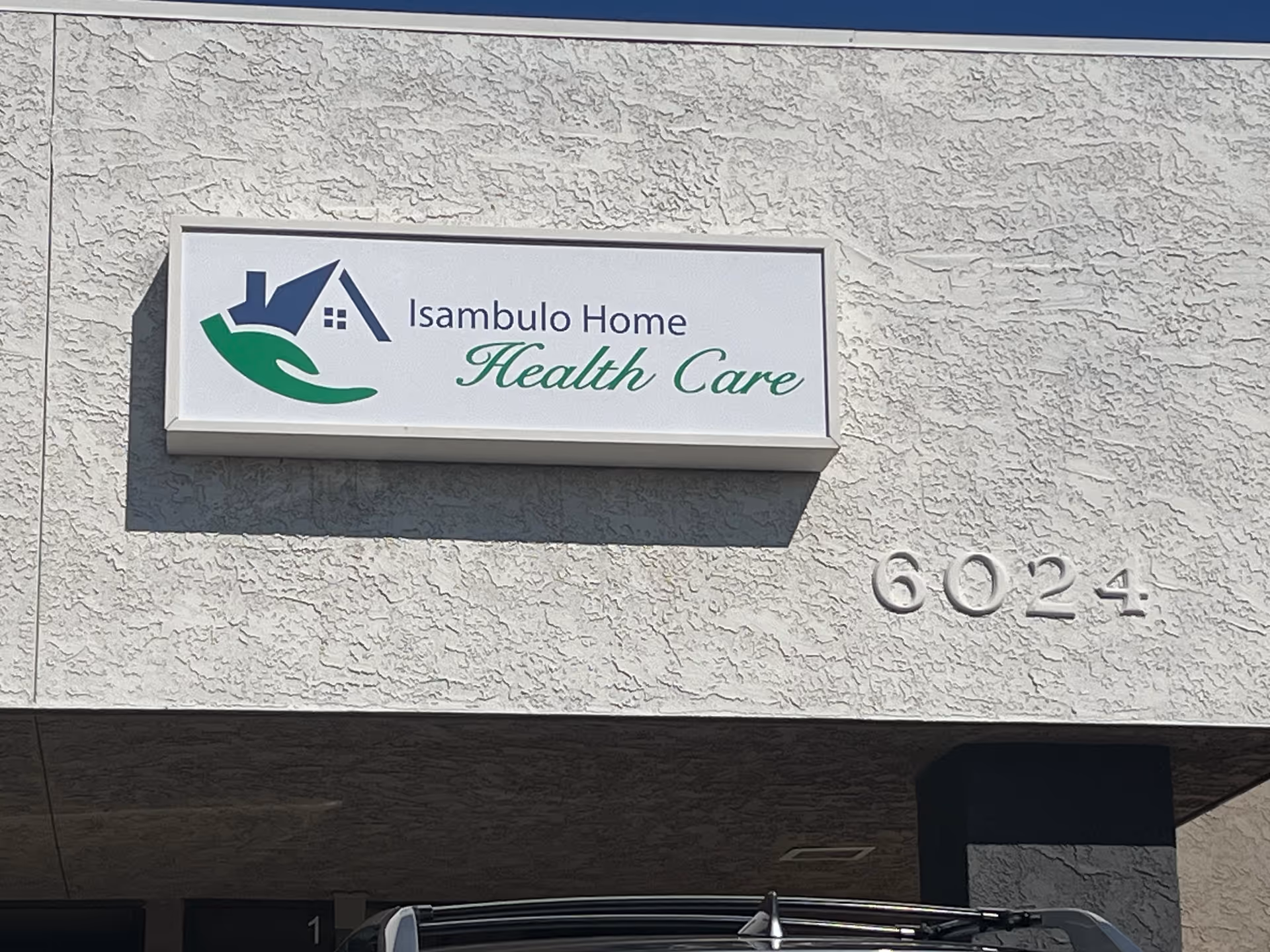 Exterior wall with Isambulo Home Health Care sign and 6024 address