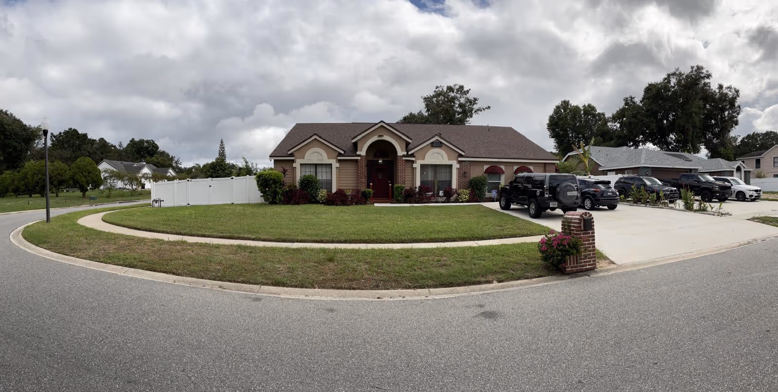 Front view of Trinity assisted living facility with curved driveway and parked cars.