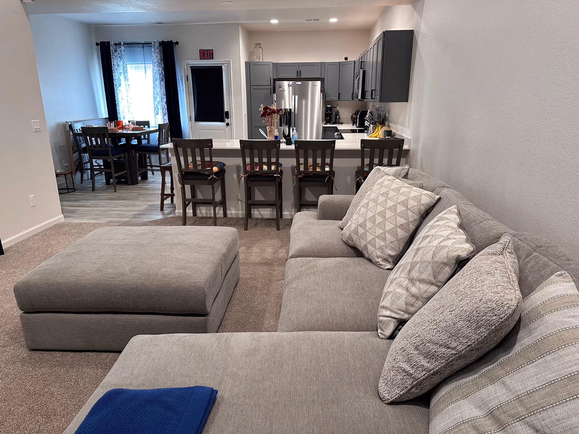 Open-concept living area with gray sofa, kitchen island, and dining table.