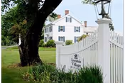 White building front with a white picket fence and Loomis Village sign.