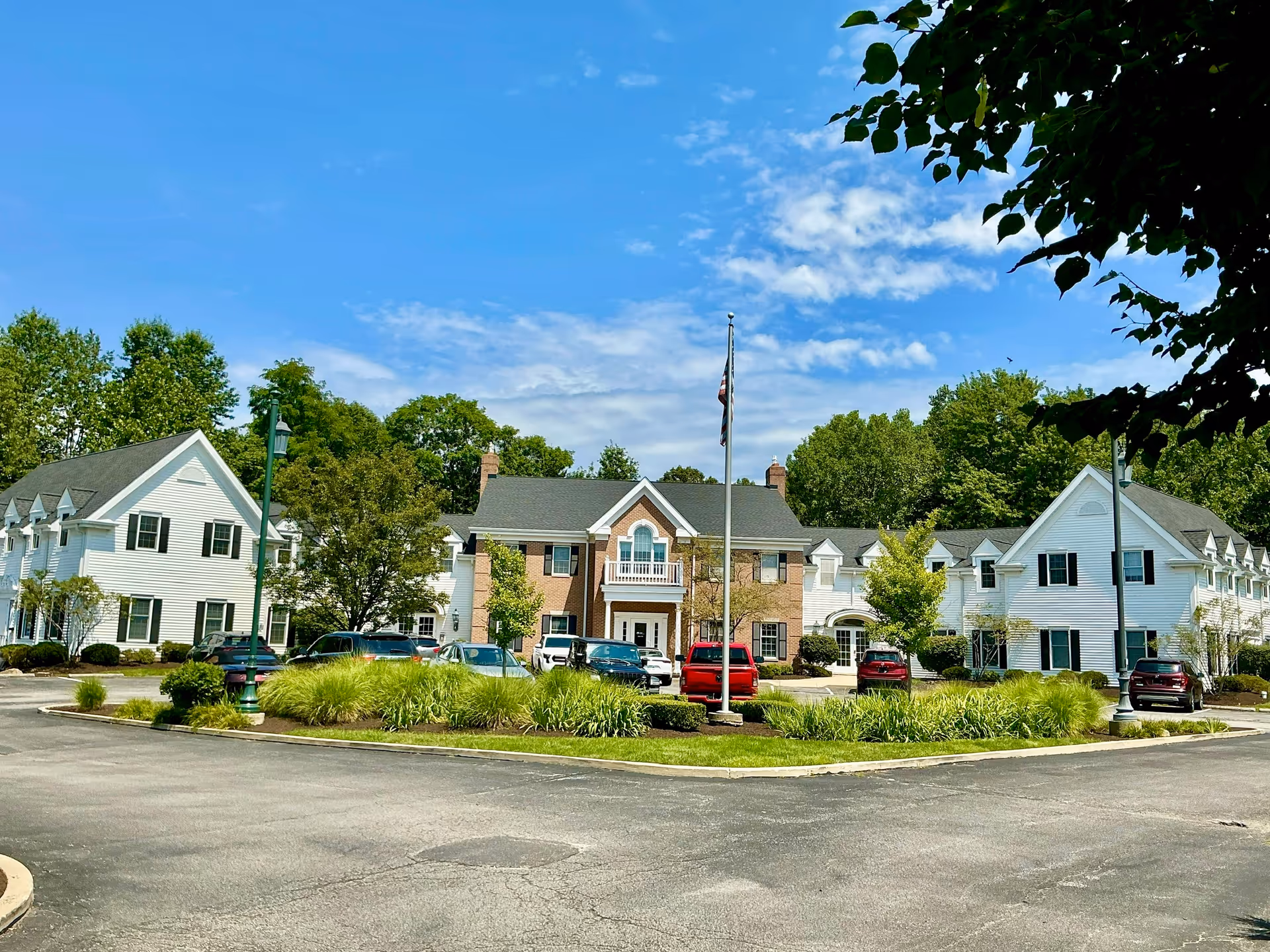 Exterior view of a senior living campus with a circular driveway and parked cars.