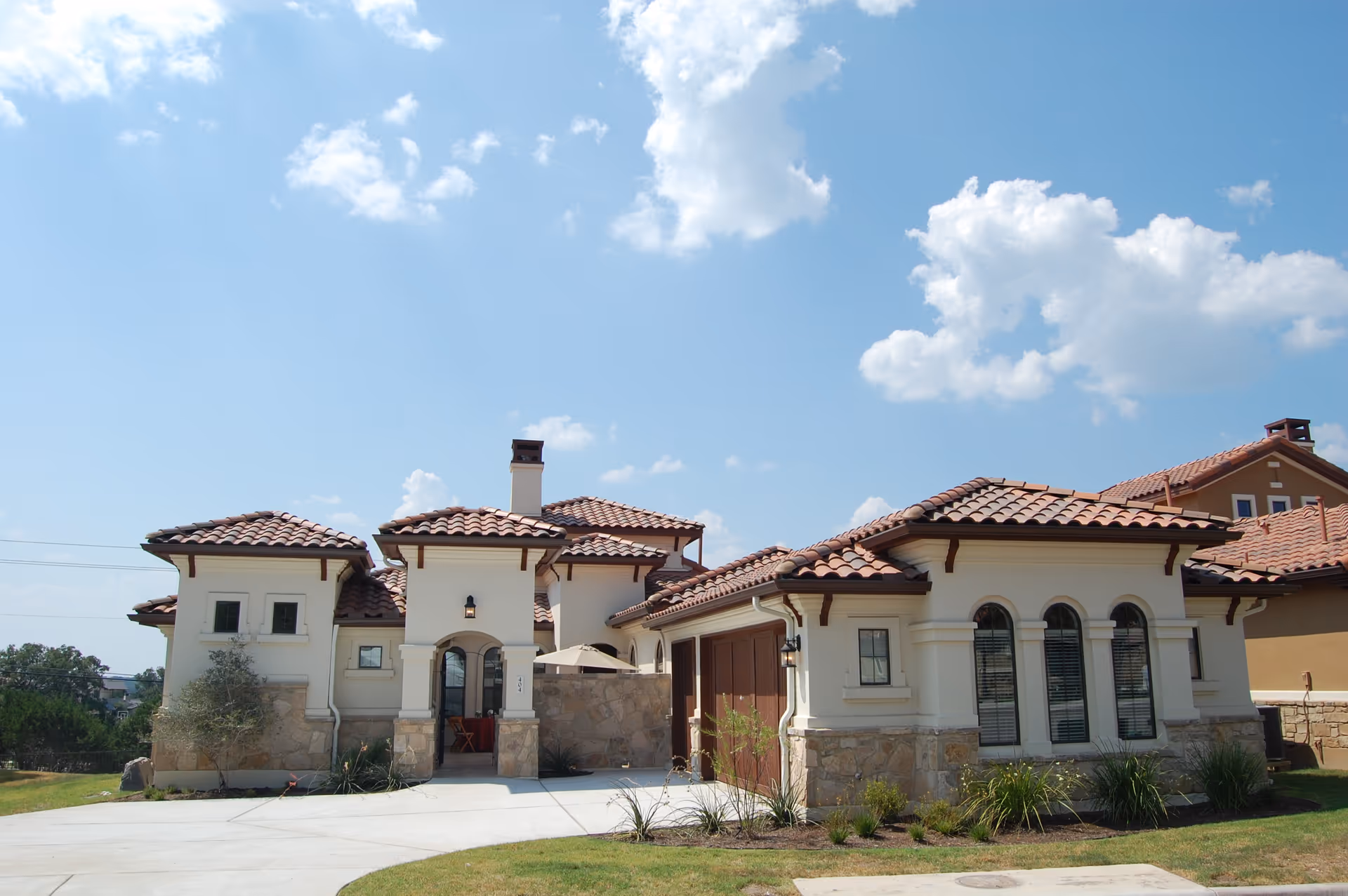Exterior view of a cream-colored senior living campus with red-tiled roofs.