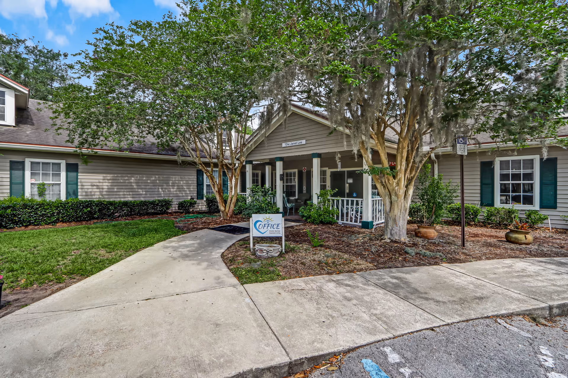 Exterior view of a senior living facility entrance with a covered porch and greenery
