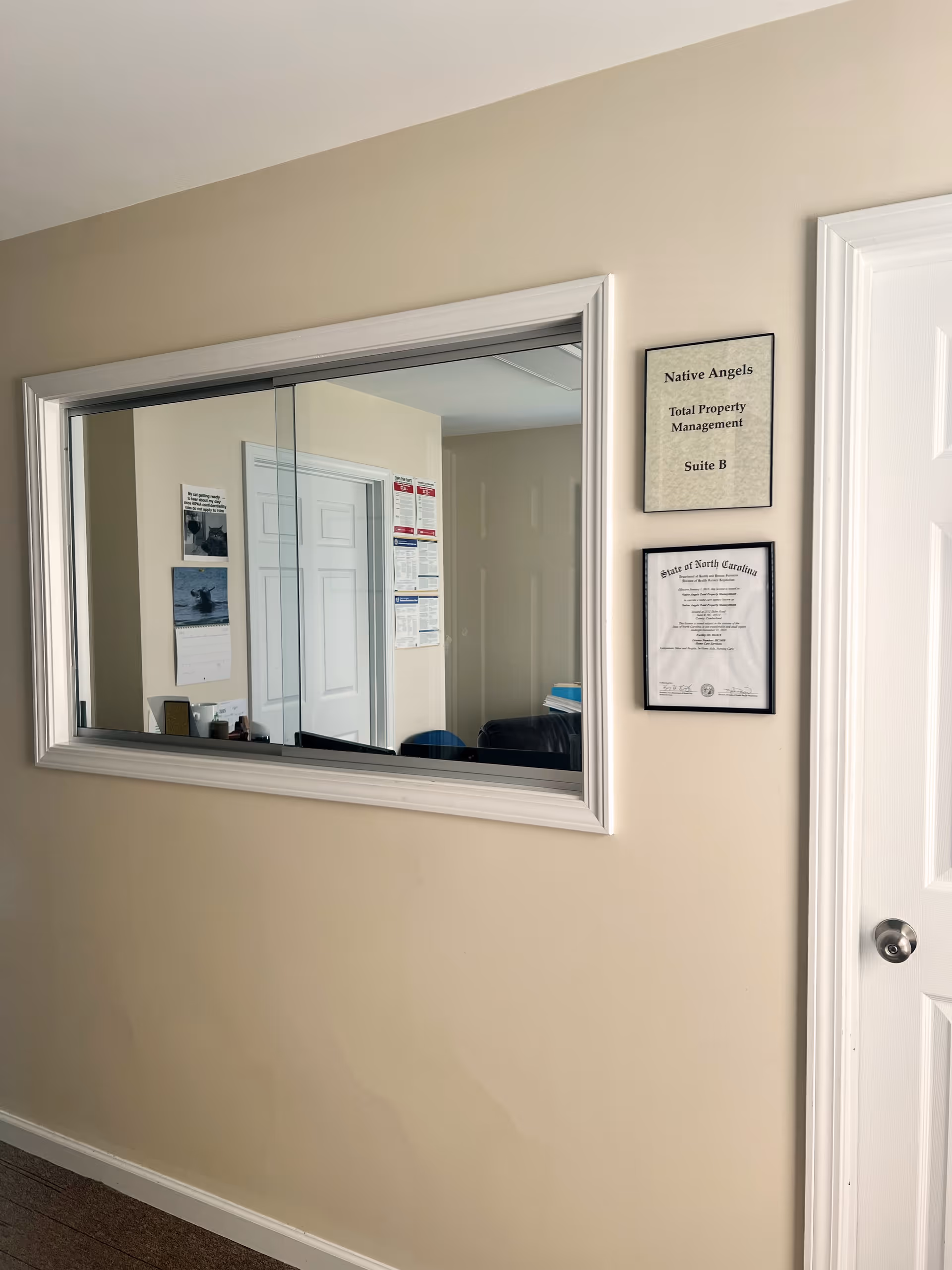 Beige hallway with a large windowed pass-through and framed certificates.