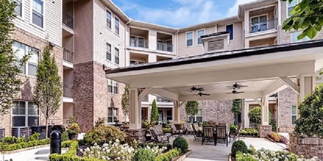 A sunlit courtyard with outdoor seating under a covered pavilion at The Legacy at Walton Heights