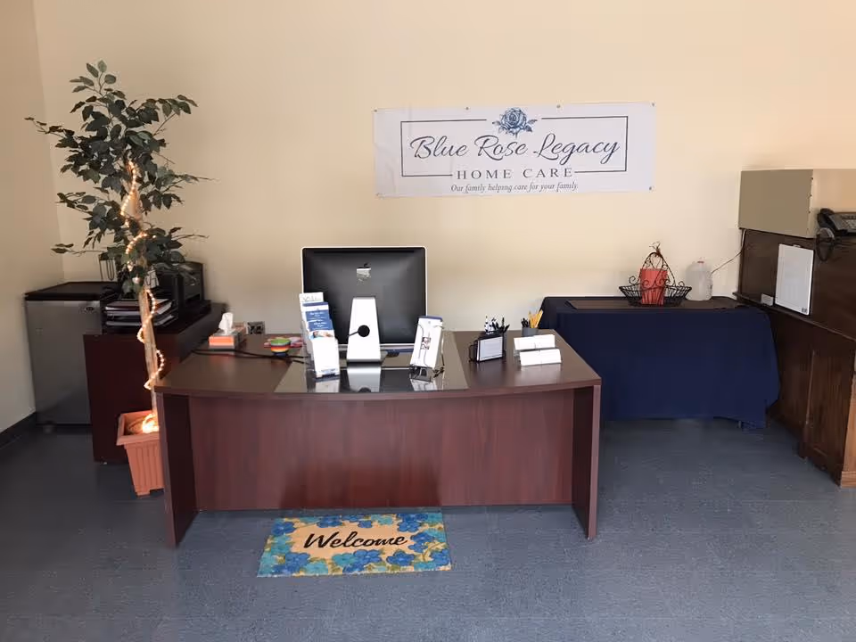 Reception desk with computer, brochures, and a welcome mat in Blue Rose Legacy Home Care lobby.