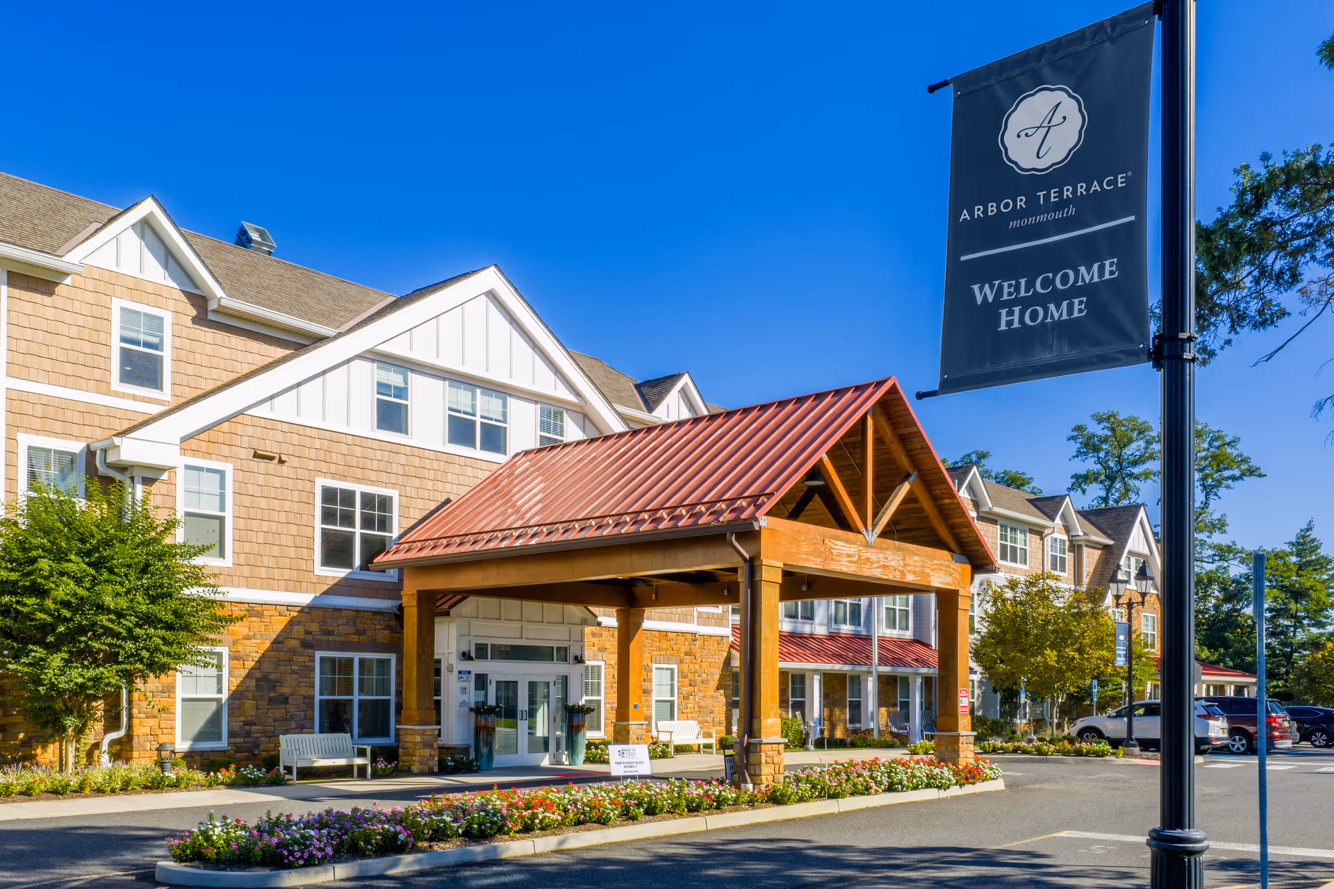 Exterior view of Arbor Terrace Monmouth facility with welcoming entrance and banner sign.