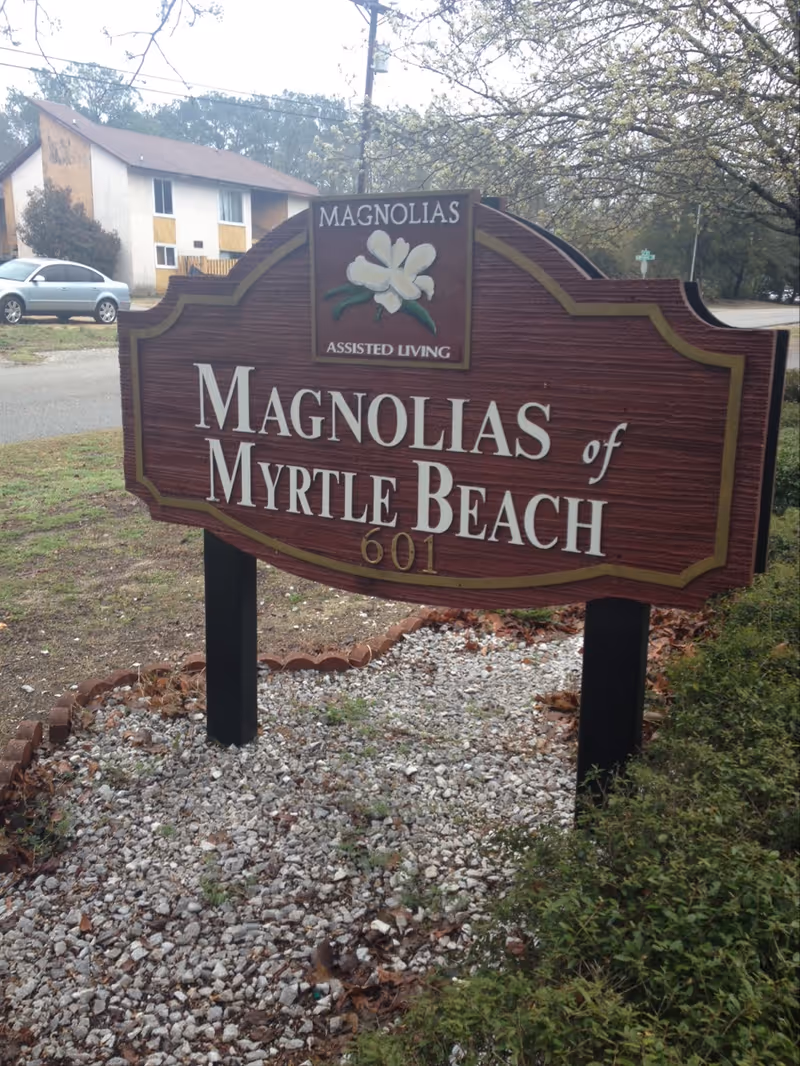 Large wooden sign for Magnolias of Myrtle Beach outside the facility.