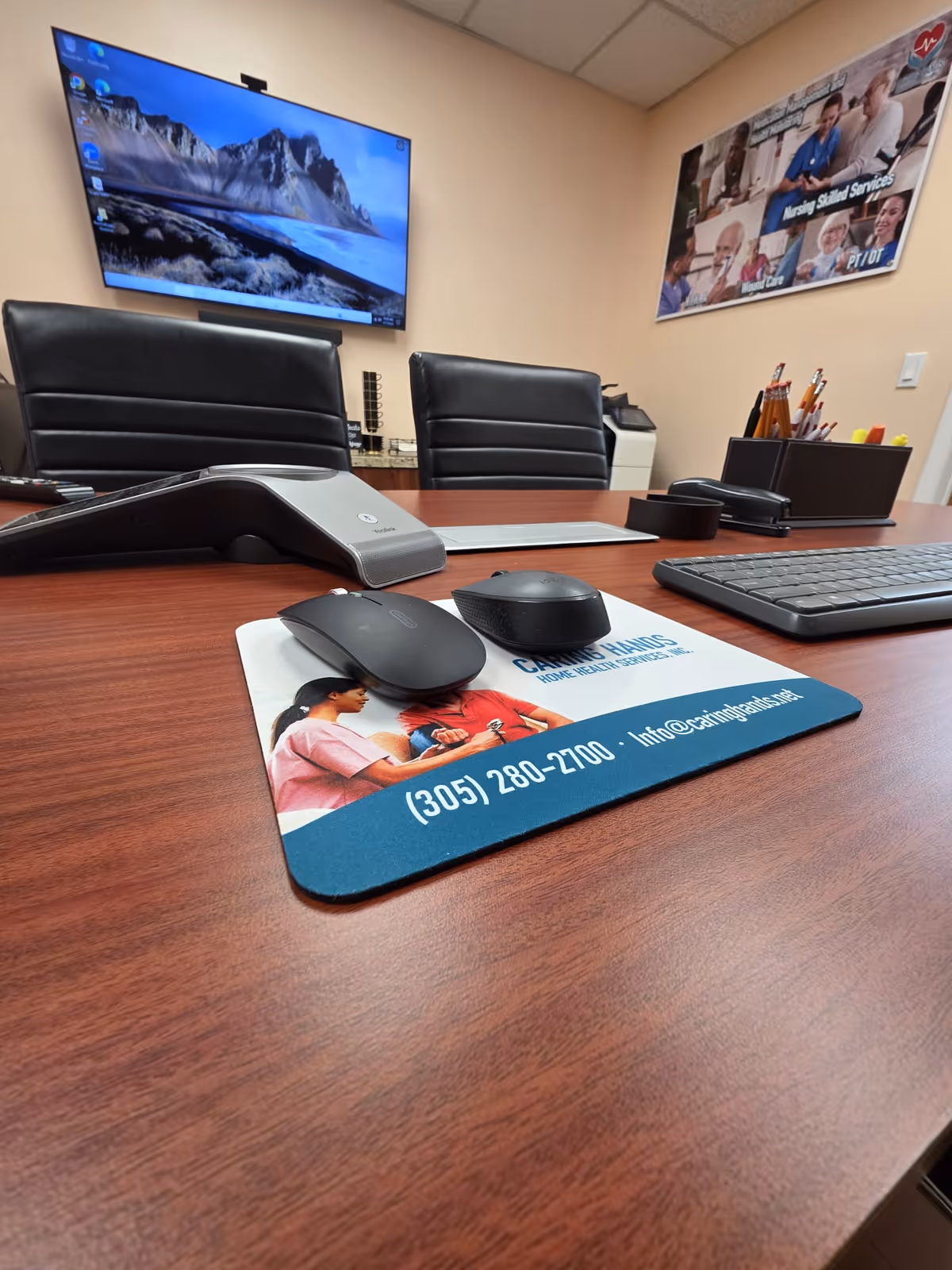 Office desk with computer setup and Caring Hands mouse pad in a home health services facility.
