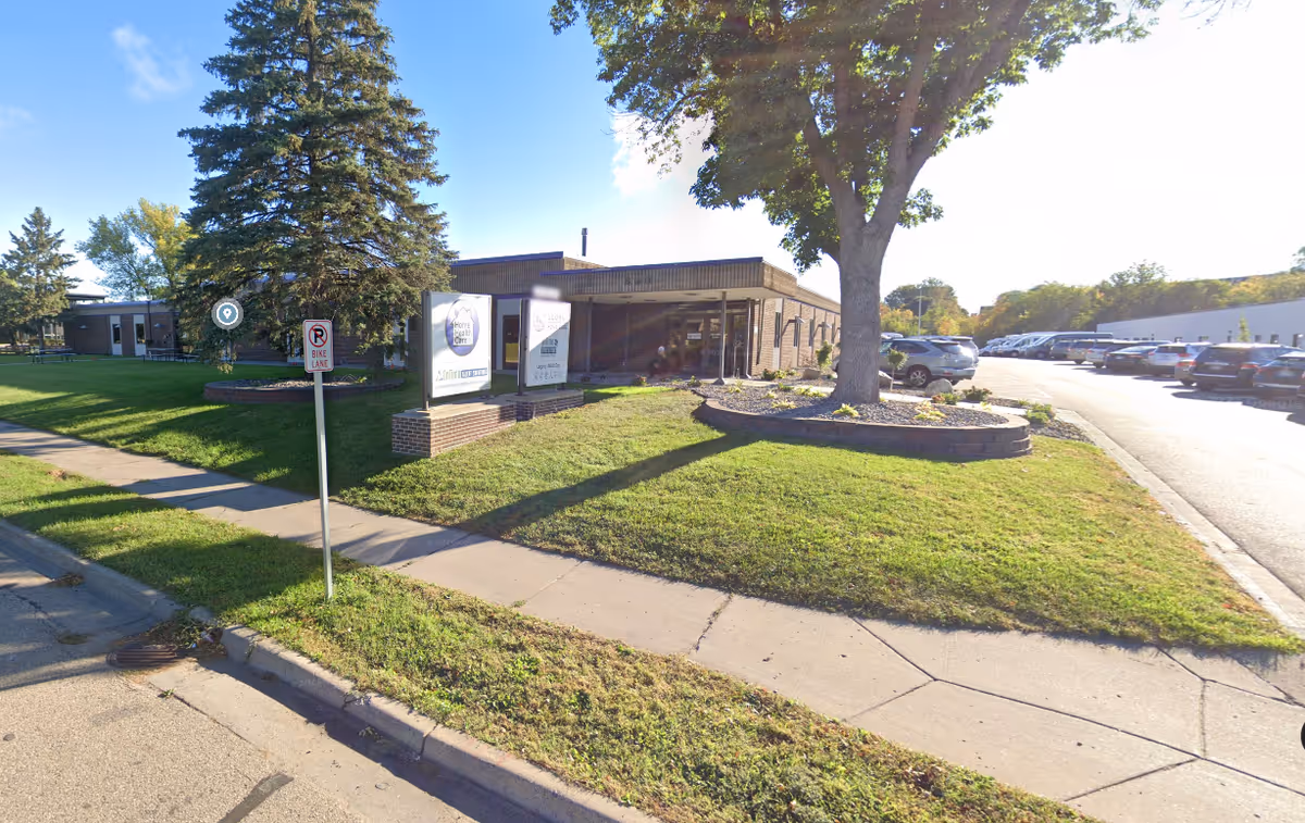 Exterior view of Superior Hospice facility with lawn, trees, and a parking lot.