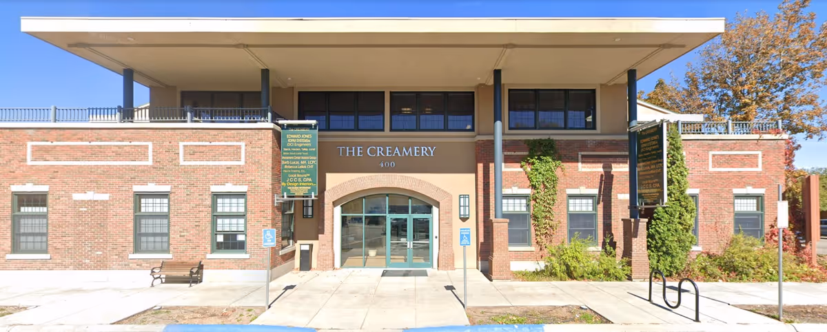 Exterior brick building front with glass entrance and The Creamery signage.